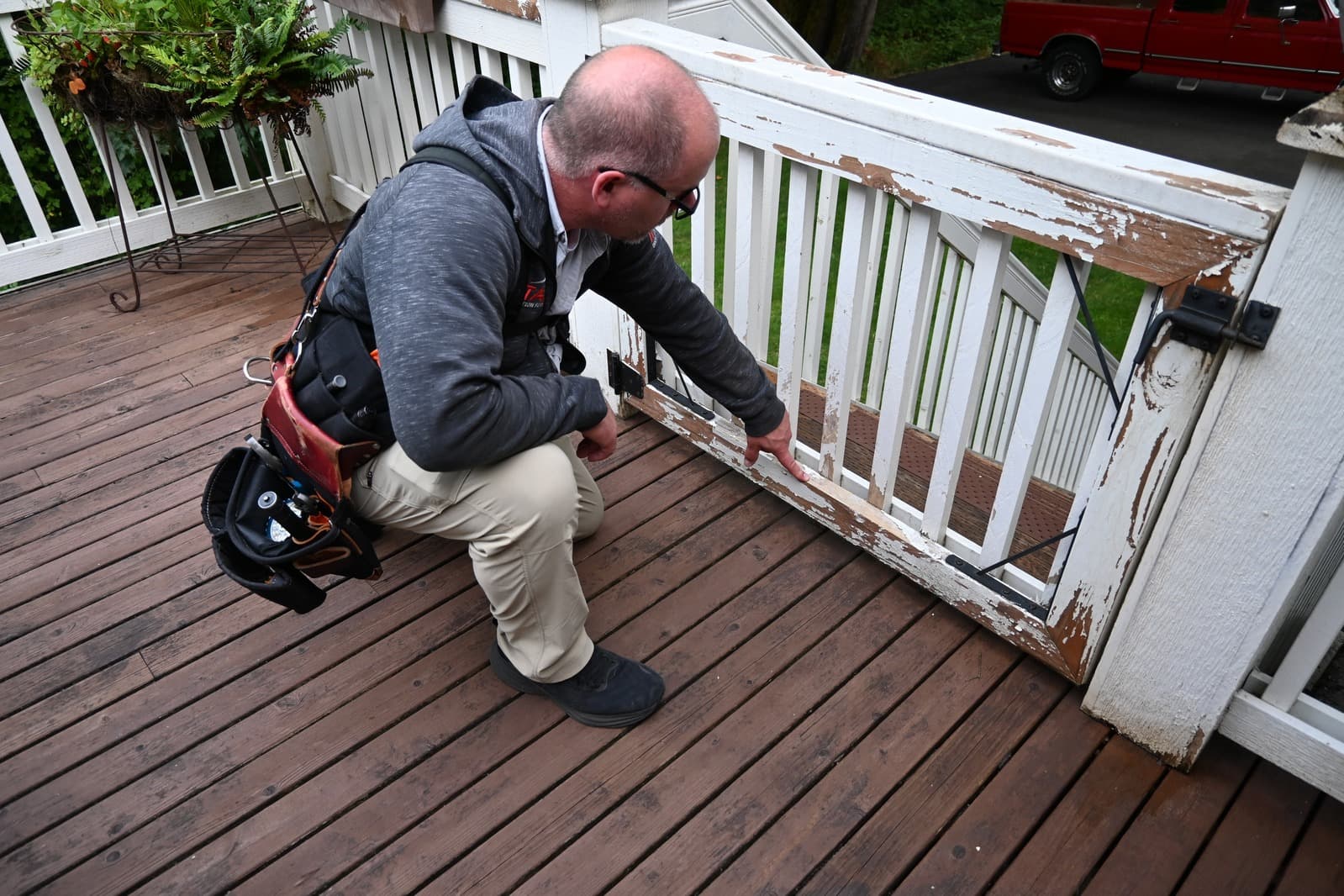 Brian, owner of Titan Inspection Services, examining peeling paint and water damage on a deck railing during a home inspection